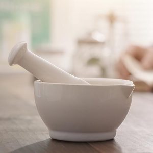 Mortar and pestle in a cream colour sitting on top of a brown surface