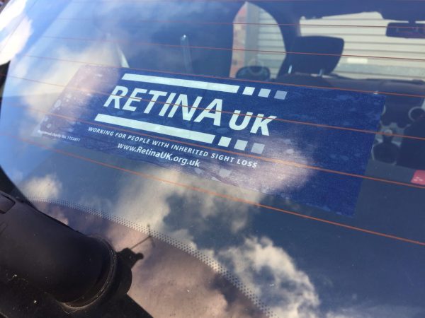 A car sticker in blue with white writing stuck on the rear screen of a car