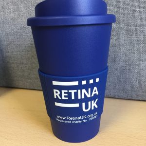 Retina UK insulated coffee cup in navy blue with the cuff showing the Retina UK logo, website url and charity number'. In this image the lid of the cup is on. The image is taken looking directly at the cup.