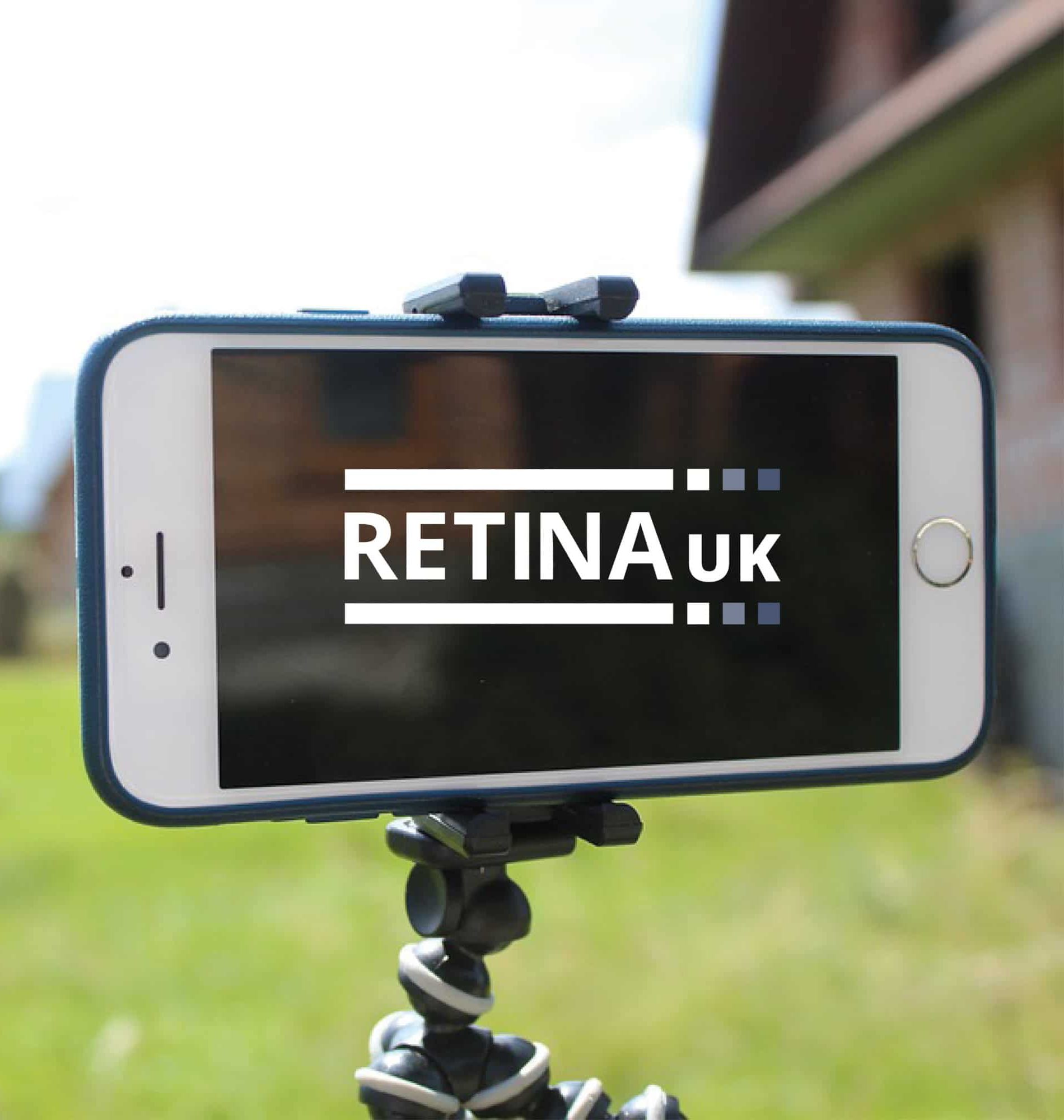 A mobile phone wiht the Retina UK logo on the screen. The phone is clamped into a tripod