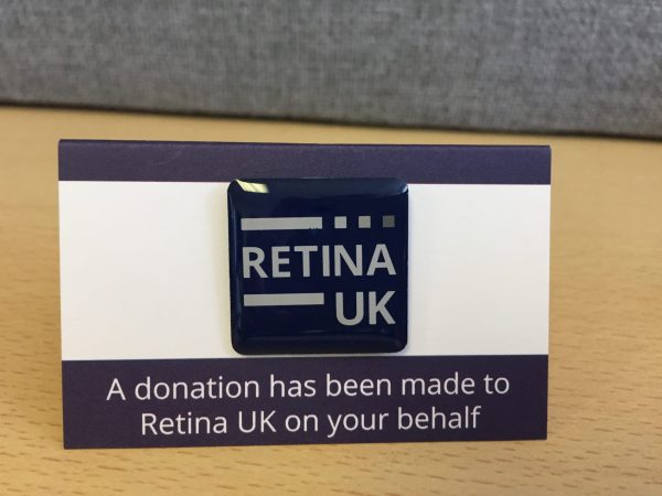 The Retina UK Pin badge mounted on card with the words 'A donation has been made to Retina UK on your behalf' printed underneath