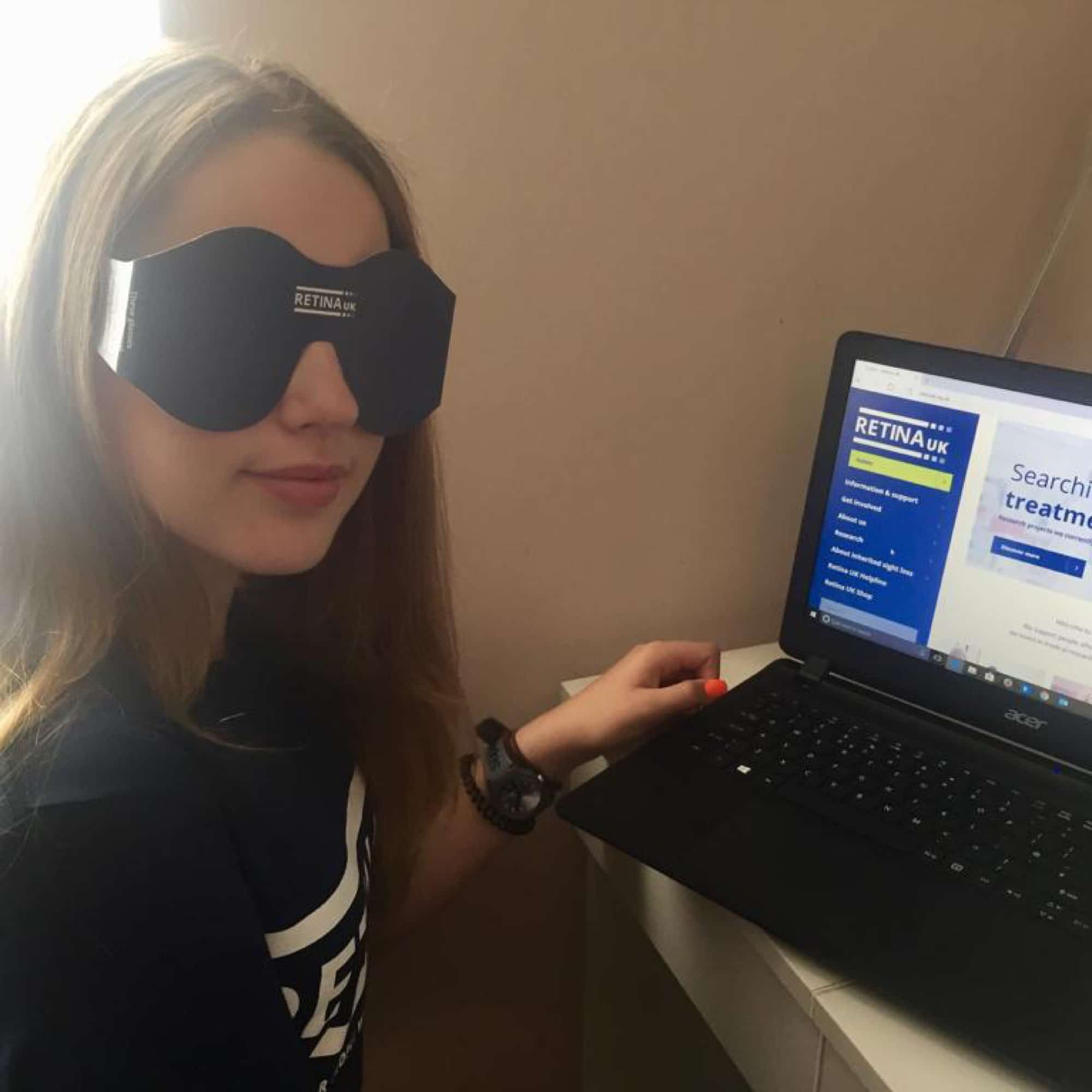 A girl wearing SIM Specs sitting in front of a laptop