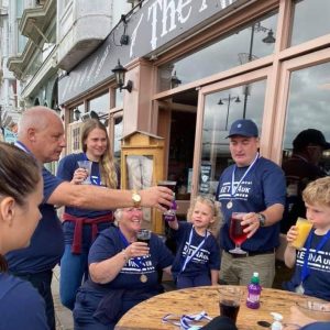 Image shows a group of walkers in blue Retina UK t-shirts raising a glass in celebration at the end of the walk.