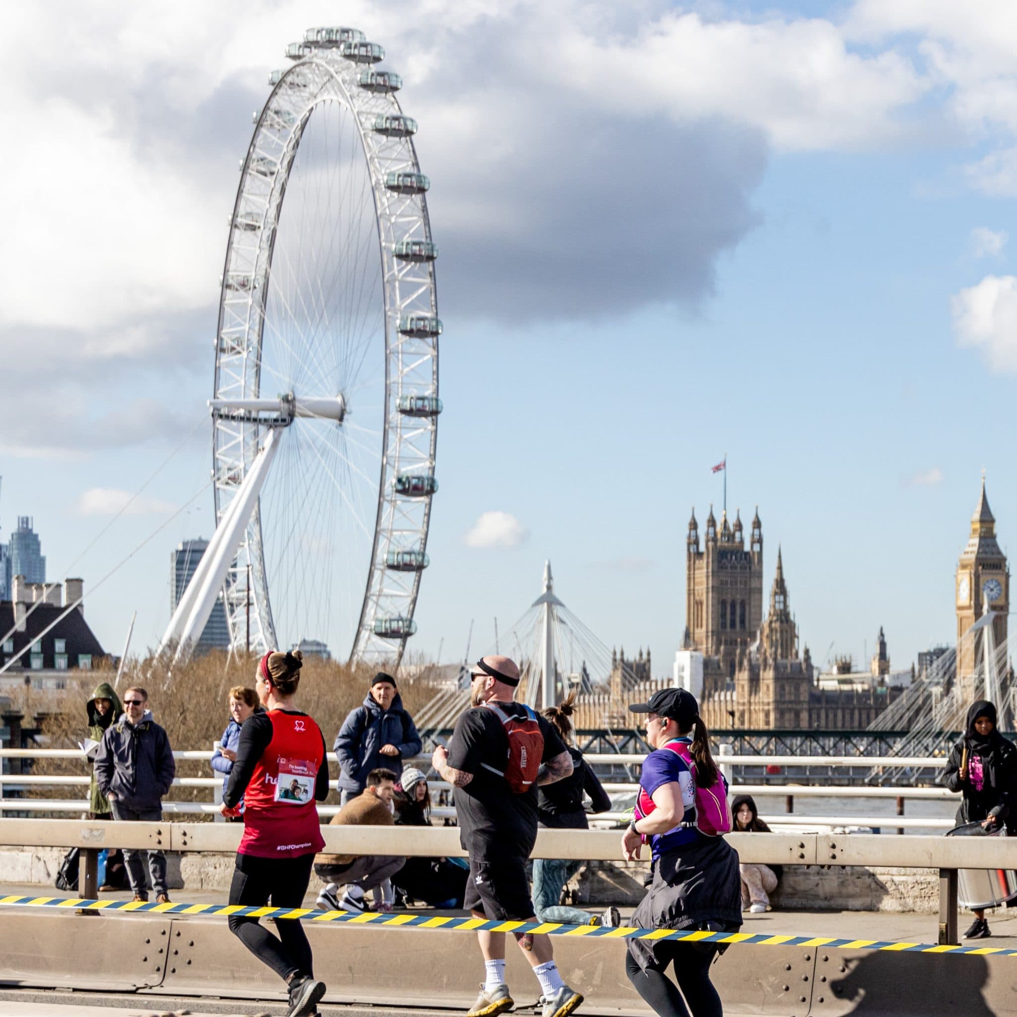 Runners are running across Waterloo Bridge with the London Eye and Houses of Parliament in the background.