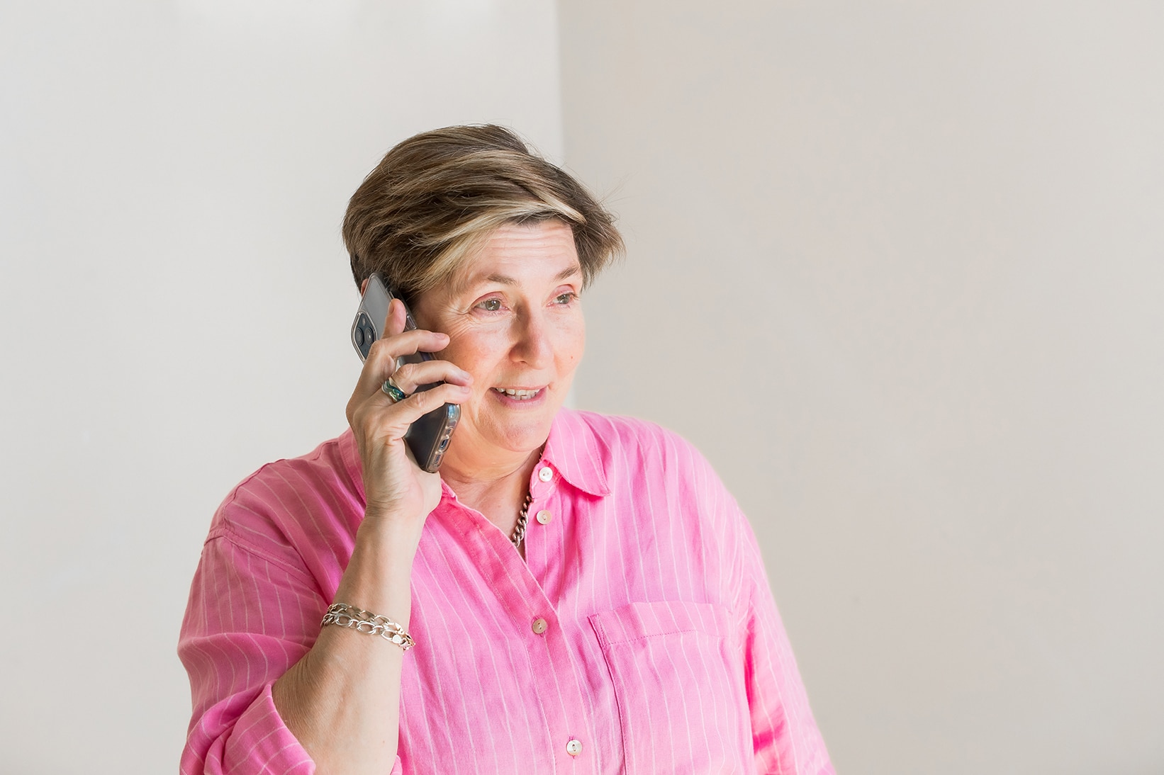 A woman wearing a pink shirt talking on the phone