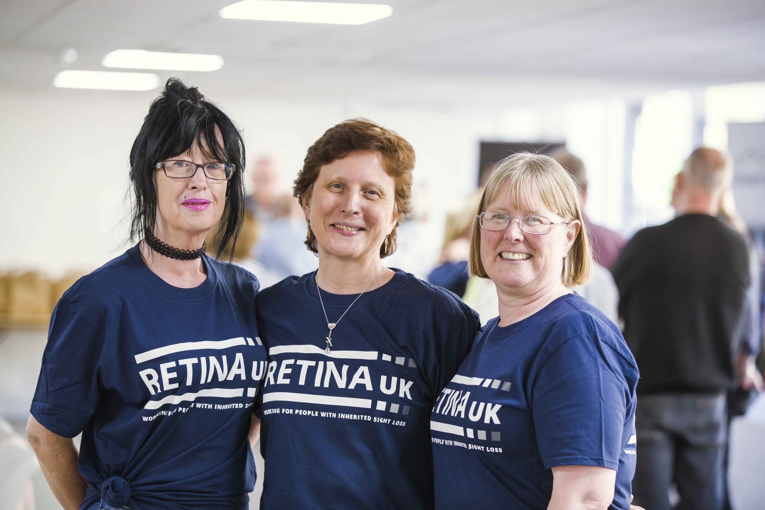 Three ladies all wearing Retina UK t-shirts. They are smiling at the camera