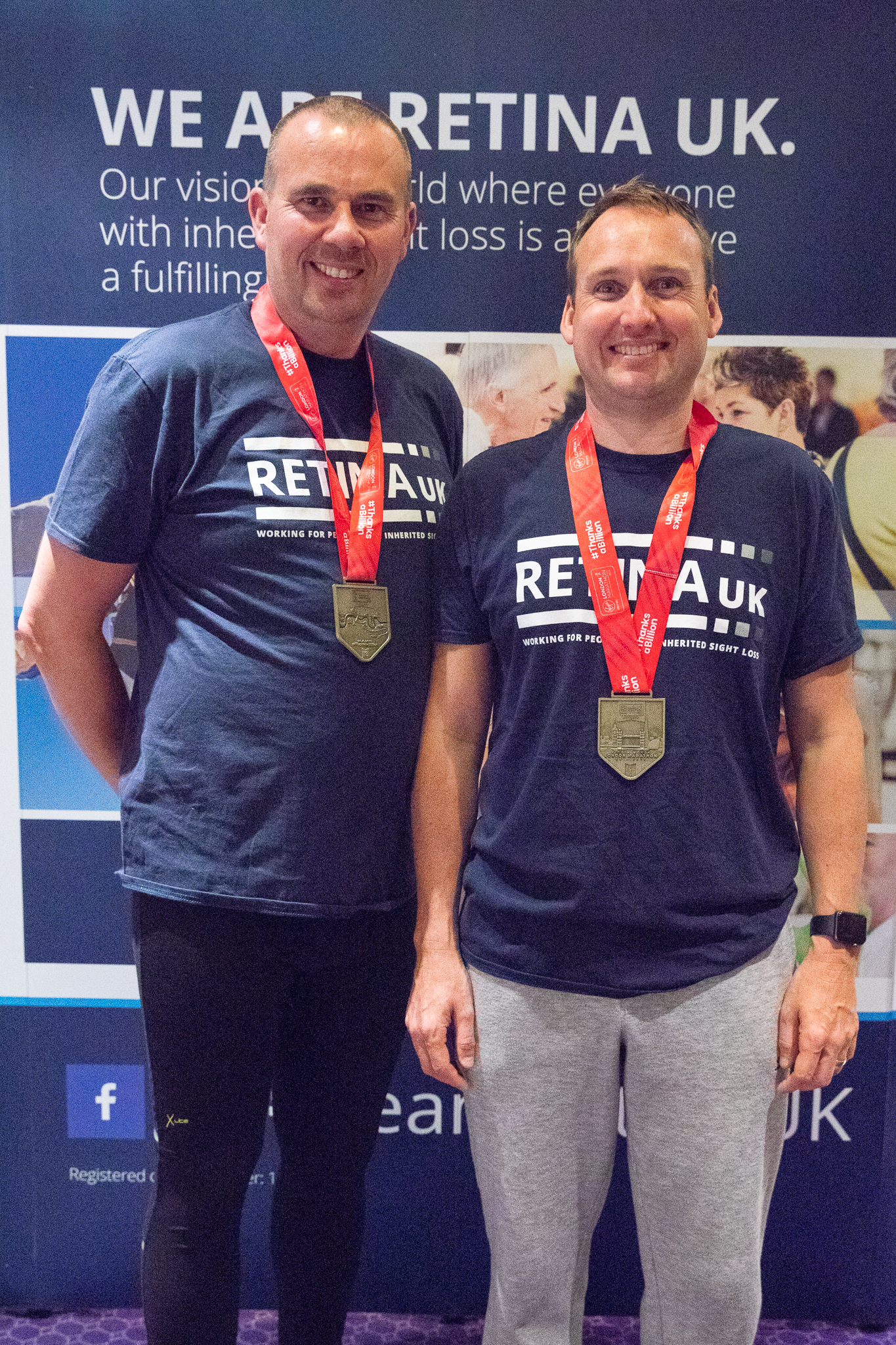 Ashley and his guide runner wearing Retina UK tshirts. They have medals hanging around their necks