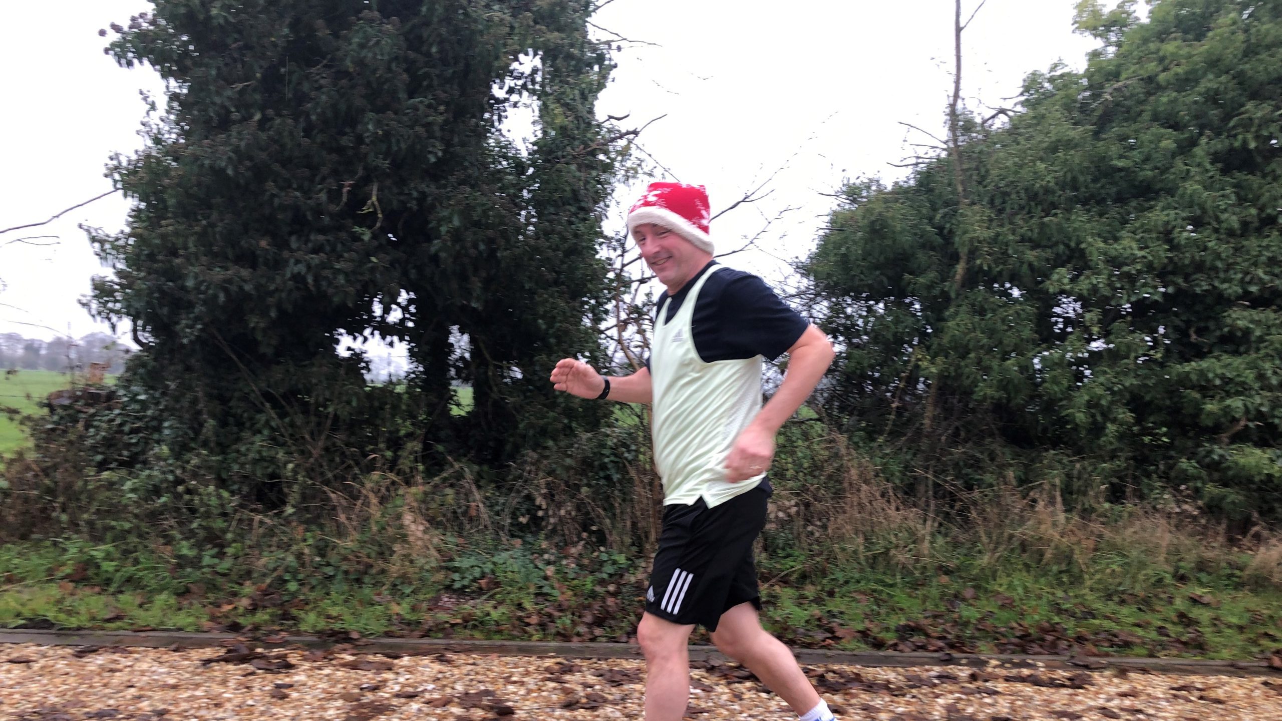 Ian Shorthose wearing a santa hat with shorts and a tshirt running