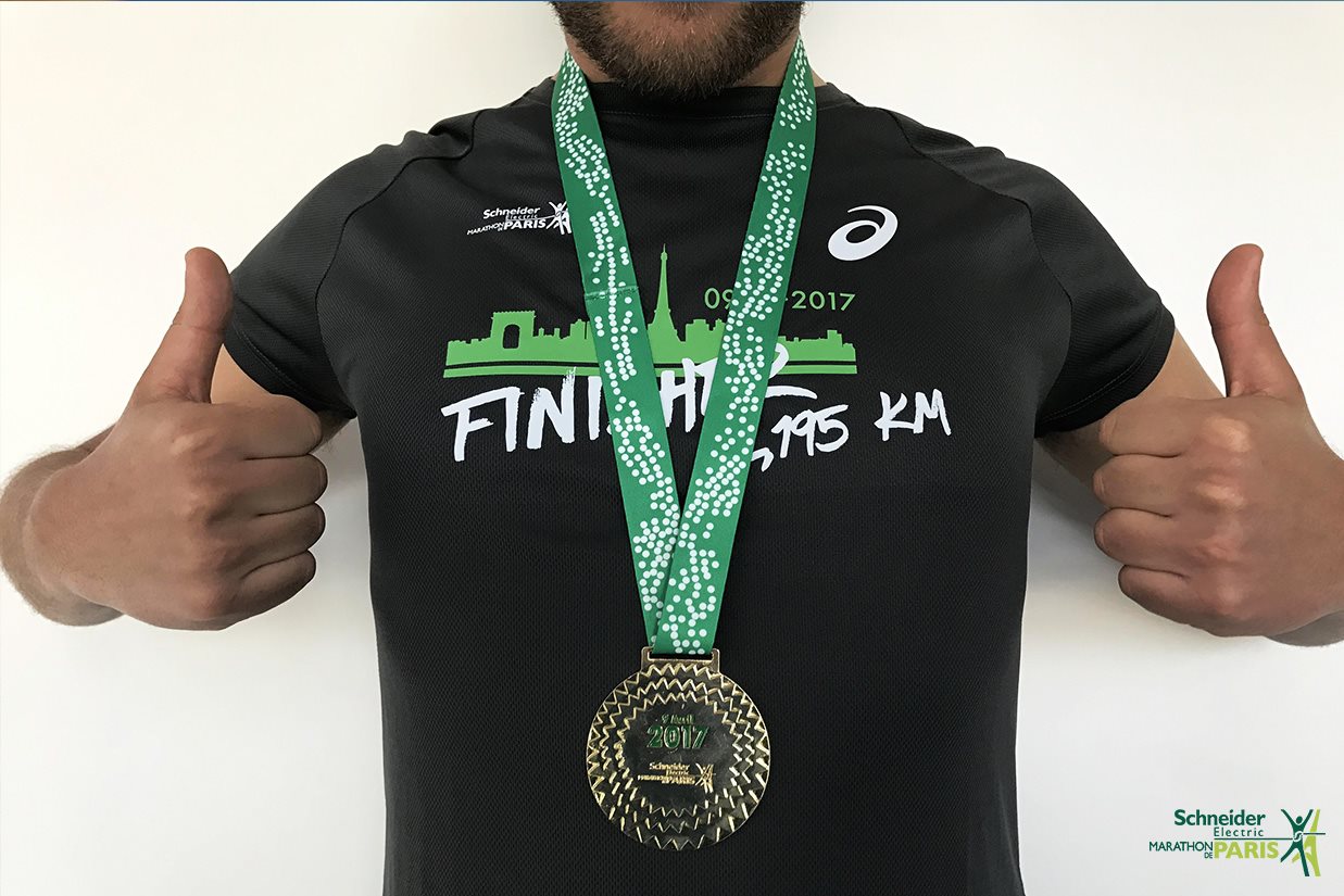 A man wearing a black tshirt with a medal around his neck on a green ribbon