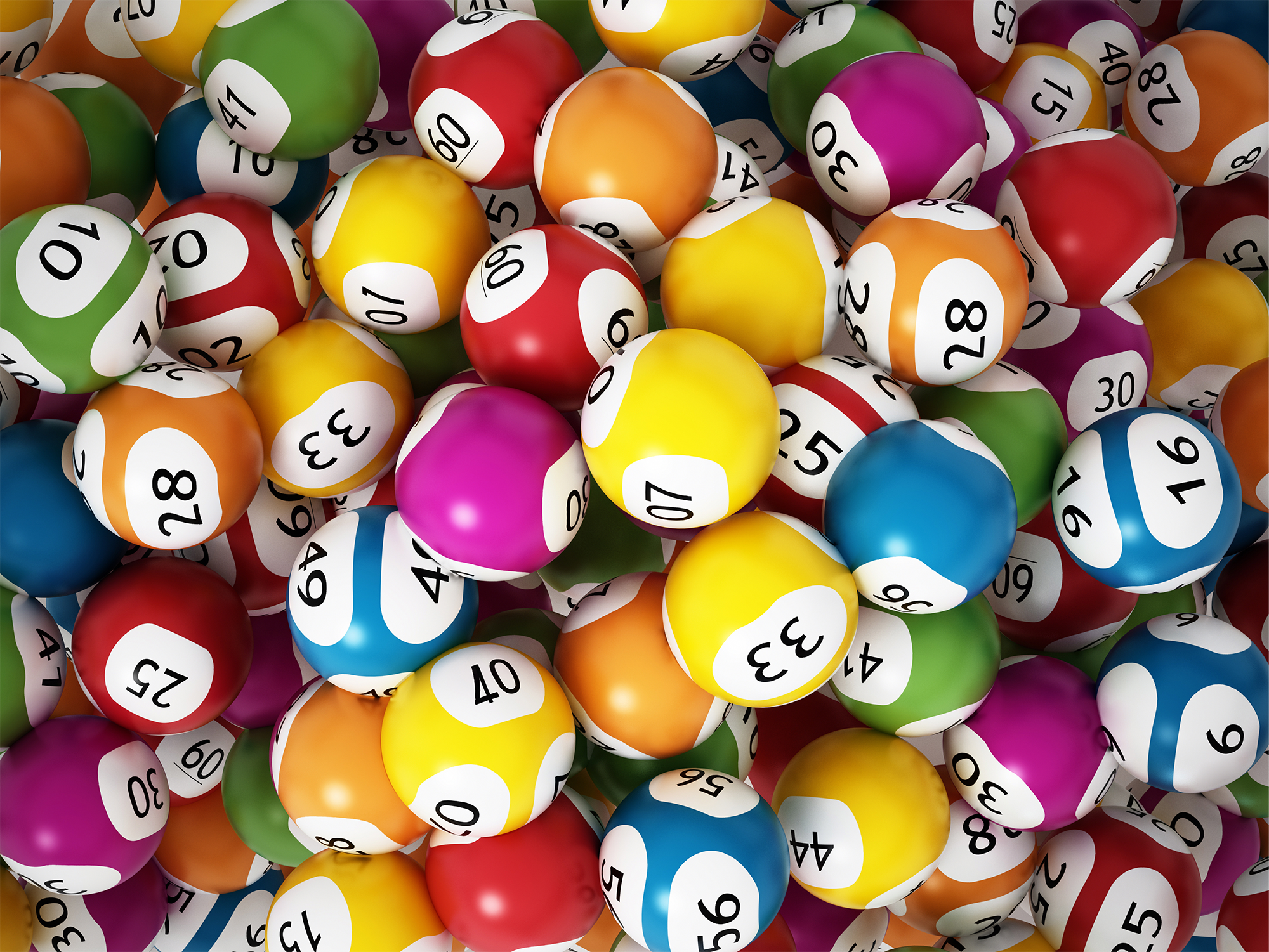 Lottery balls in lots of different bright colours with different numbers printed on them in black