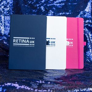 A navy, pink and white notebook with the Retina UK logo on the front.