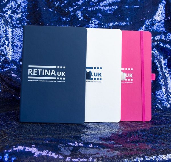 A navy, pink and white notebook with the Retina UK logo on the front.