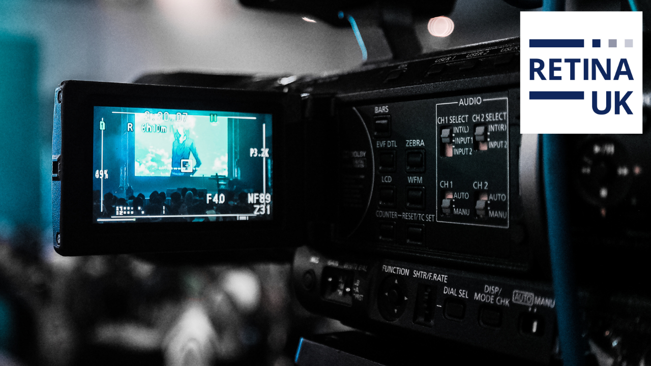 A large video camera with a mini screen shown in the foreground. The background is blurry.