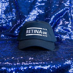 side view of Navy baseball cap with Retina UK logo in white