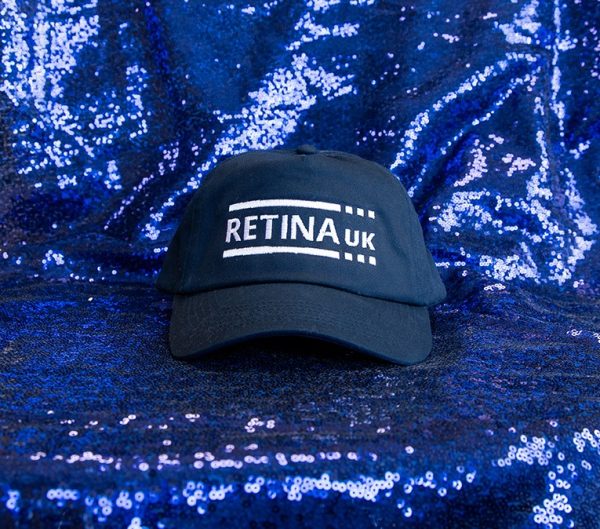 side view of Navy baseball cap with Retina UK logo in white