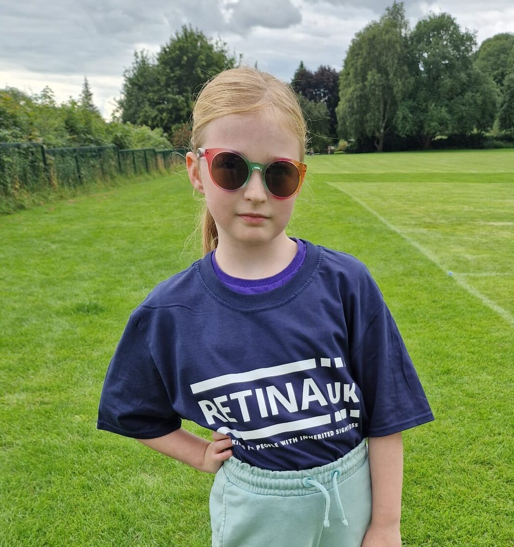 A young girl wearing sunglasses and a Retina UK t-shirt.